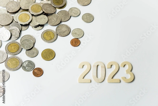 Fototapeta Wooden text of 2023 with coins, money saving concept, financial and business growth, white background