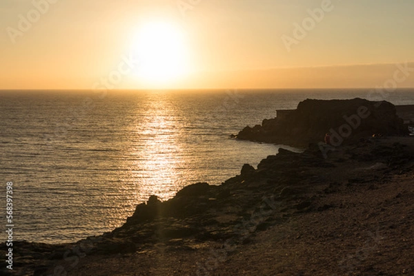 Fototapeta backlit seascape, beautiful golden sunset over the sea from the cliffs. El Cotillo, Fuerteventura, Canary Islands, Spain