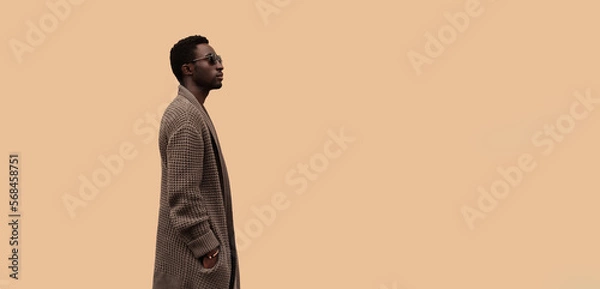 Obraz Fashionable portrait of stylish african man model looking away wearing knitted cardigan isolated on brown background, profile view, blank copy space for advertising text