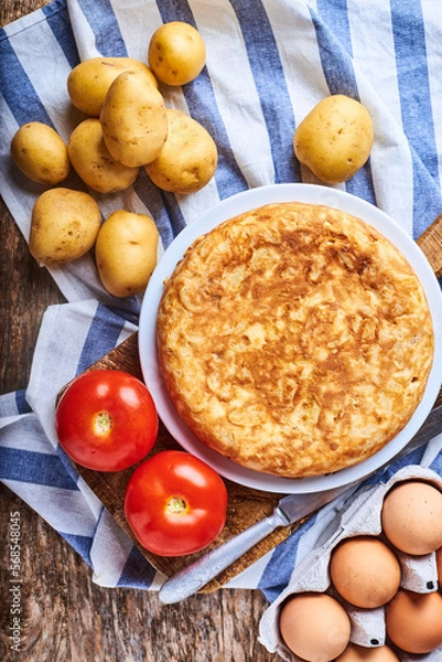 Fototapeta Tortilla de patatas con sus ingredientes recien hecha y casera en una imagen cenital.