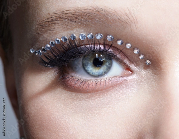 Obraz Closeup macro shot of human female eye with unusual makeup. Woman with rhinestones arrows on eyelid.