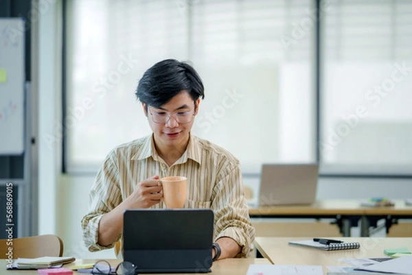 Obraz Young asian businessman sitting working with laptop computer in office