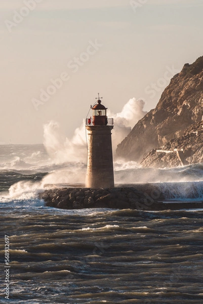 Fototapeta giant waves crashing on rocks and into a lighthouse, covering the building 