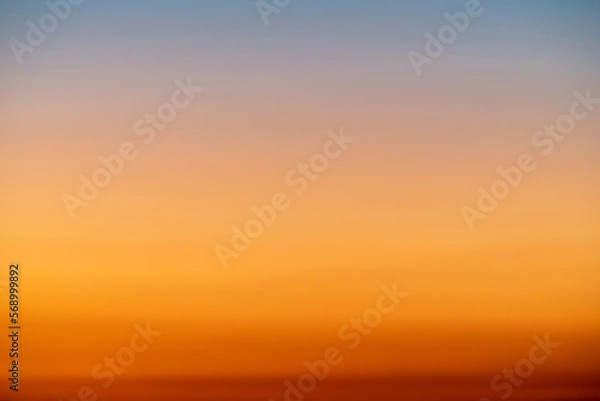 Fototapeta The dramatic colors of the sunset in the sky gradient from blue to orange.
