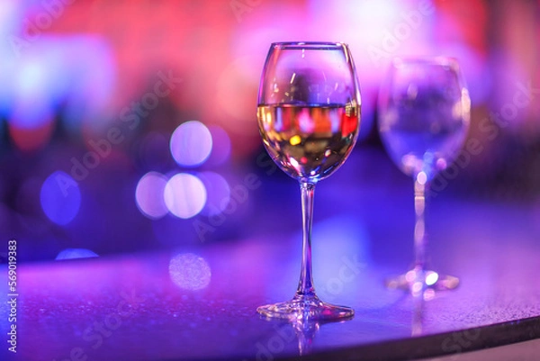 Fototapeta A glass of champagne on the background of lights from the garland. 