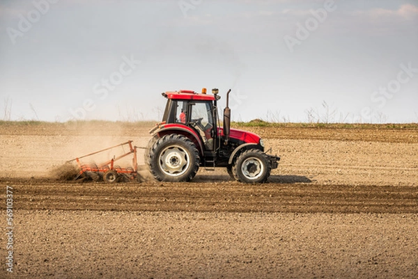 Fototapeta Fields of possibility, tractor readying the earth for a bountiful harvest