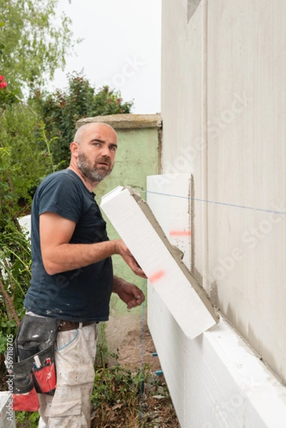 Obraz Construction worker working on house exterior wall