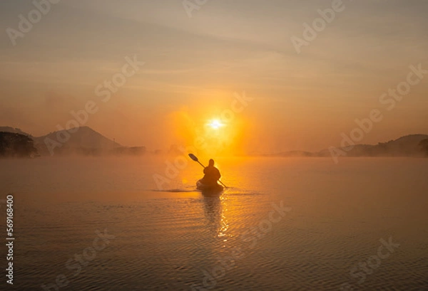 Fototapeta Women on kayak rows in the reservoir during the sunrise, Harirak forest park Huai Nam Man reservoir Loei Thailand 21 Jan 2023
