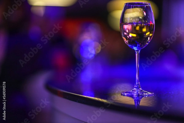 Fototapeta A glass of champagne on the background of lights from the garland. 