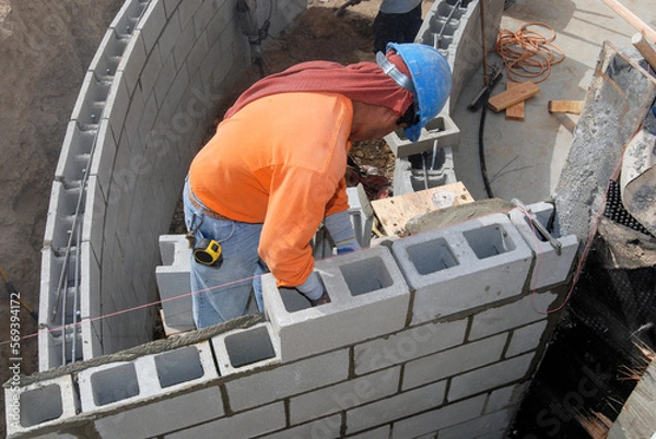 Fototapeta Mason installing a structural block retaining wall