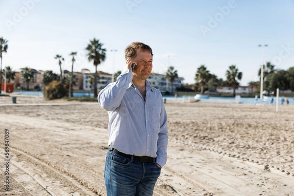 Fototapeta Businessman Talking On Phone, using smartphone mobile apps texting message, surfing social media tech standing in urban city on modern street outdoors.