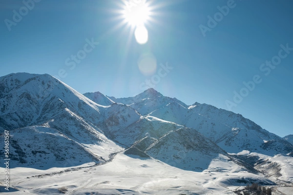 Fototapeta Panoramic view of snowcapped mountains illuminated by the sun. Winter. beautiful clear blue sky in daylight. impressive view of the mountain peaks