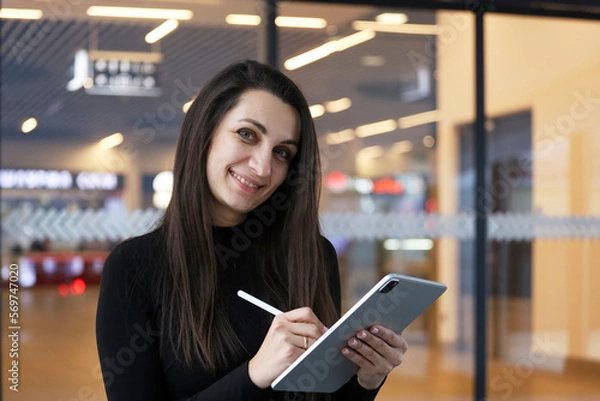 Fototapeta beautiful business woman using tablet computer texting while walking in corporate office building, checking e-mail messages the internet, successful executive woman.