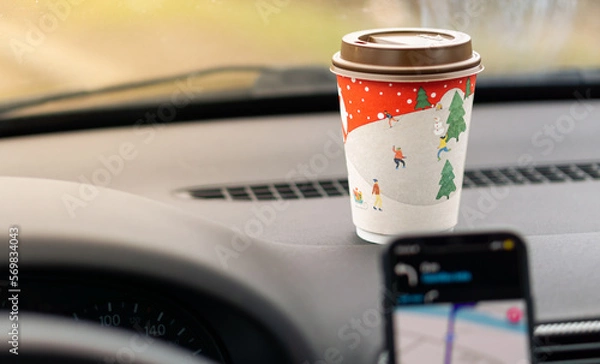 Fototapeta Takeaway paper cup with coffee in front of the car and navigation in the phone