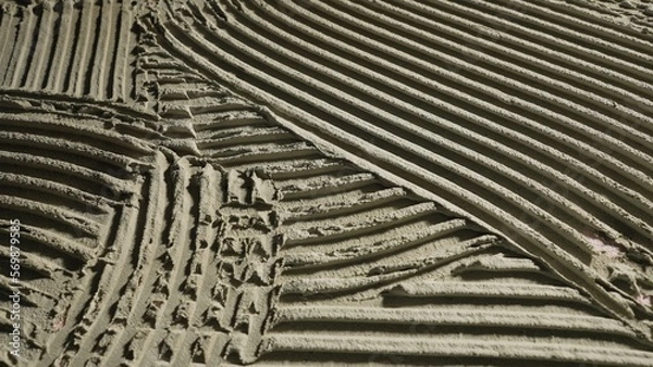 Fototapeta Fresh concrete texture with patterns of notched trowel. Macro shot of grey surface cement putty on wall with horizontal lines or stripes. Tile installation. Repair work, finishing, decor.