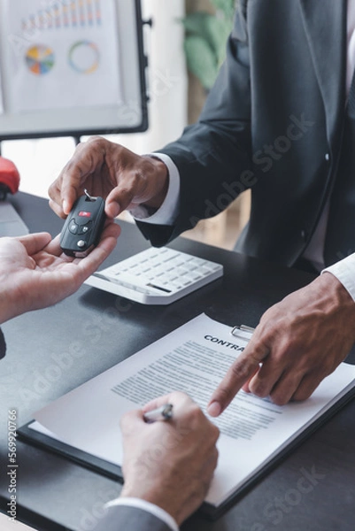 Fototapeta Concept of Car insurance or rental, salesman is making deal with buyer and giving key to him after sign sell contract or rental agreement.