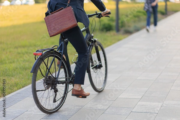 Obraz Stylish business man in suit cycling on bike on paved road outdoors.