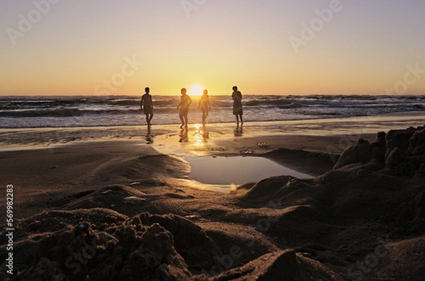 Obraz niños y sus padres corriendo hacia el mar al atardecer