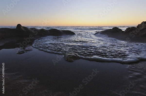 Obraz olas del mar entrando por las figuras de la arena, puesta de sol en la playa