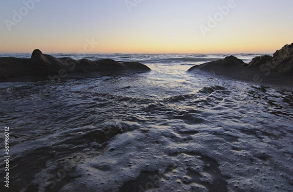 Obraz olas del mar entrando por las figuras de la arena, puesta de sol en la playa