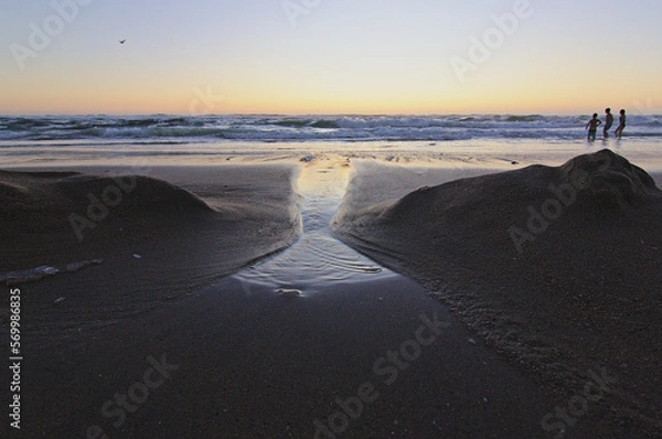 Obraz olas del mar entrando por las figuras de la arena, puesta de sol en la playa