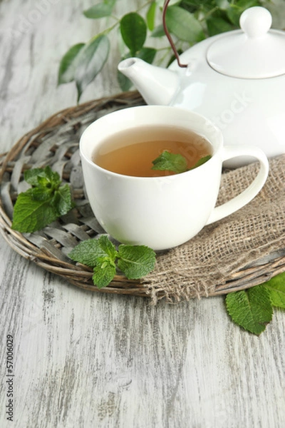 Obraz Teapot and cup of herbal tea with fresh mint on wooden table