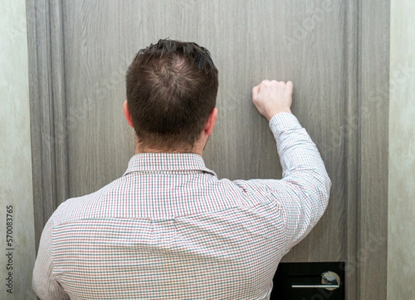 Obraz An elegant man, rear view from the back in a shirt is knocking on the office door to the director. A business man in a shirt knocks on the door.