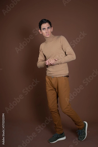 Obraz Young attractive guy fooling around in the studio. Brown background.