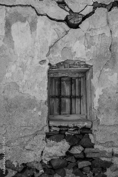 Fototapeta Black and white picture of an old window with bars in an old broken wall