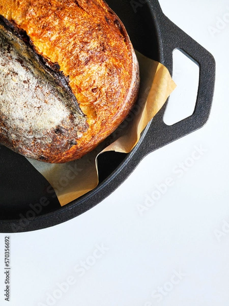 Obraz Sourdough bread in a cast iron pan right after baking. White background.