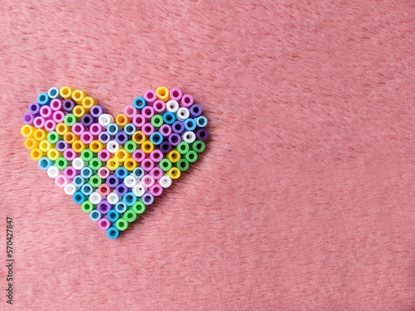 Fototapeta heart of multi-colored beads on a pink bright background for valentine's day
