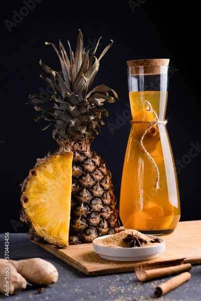 Fototapeta Pineapple Tepache. Fermented drink from pineapple served in bottle in low key. Dark background.