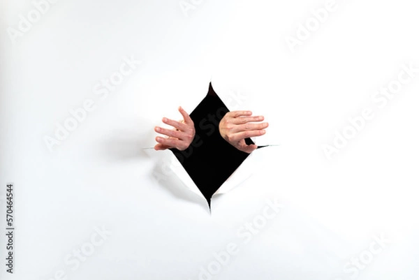Fototapeta hands reaching through paper
