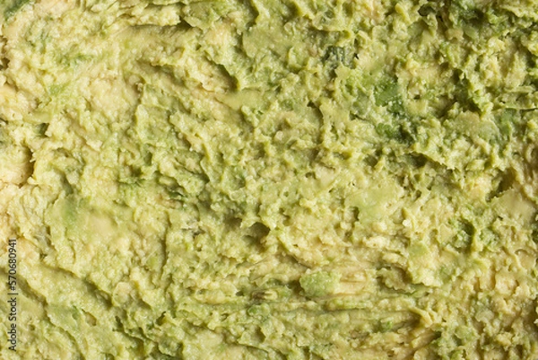 Fototapeta Close-up top view of creamy mashed avocado meat, highlighting its natural green color. Unique perspective and high-res detail promoting healthy living, nutritious meals. Organic texture background.