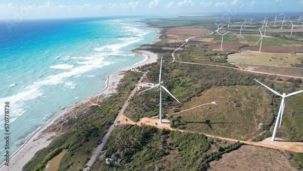 Fototapeta Wind farm shot next to caribbean beach from drone