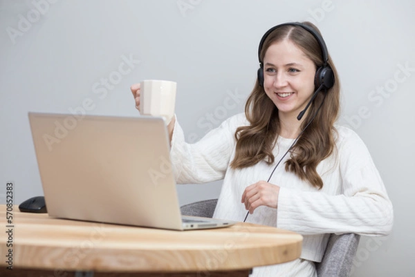 Fototapeta beautiful girl working at home with laptop and drinking hot tea with colleague