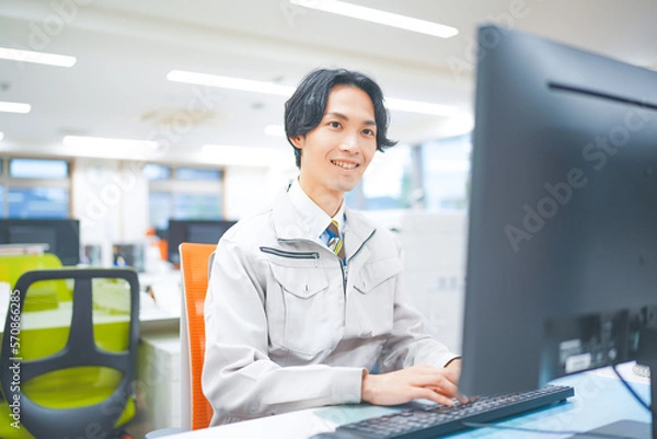 Fototapeta 作業着を着てパソコン作業をする若いエンジニアの男性
