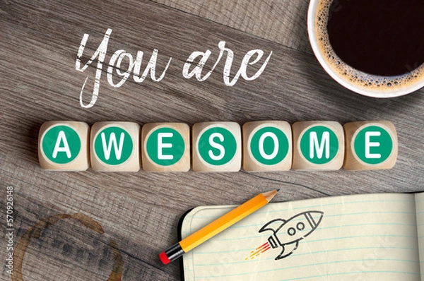 Obraz Cubes, dice or blocks with message you are awesome on wooden background with pencil, coffee and sketch book