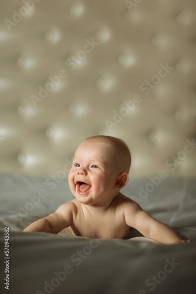 Fototapeta Portrait of a cute newborn boy, looking with interested on something while trying crawling at isolated studio
