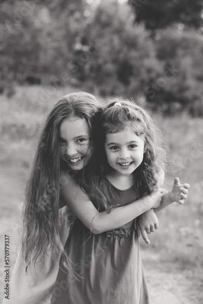 Obraz Black and white portrait of Two Happy little girls laughing and hugging at the  summer park.