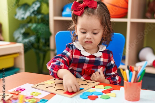 Fototapeta Adorable blonde toddler playing with maths puzzle game sitting on floor at kindergarten