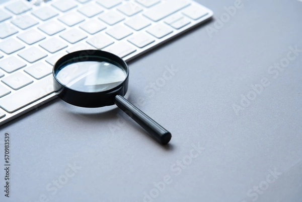 Fototapeta Network data search concept.Magnifying glass and keyboard.