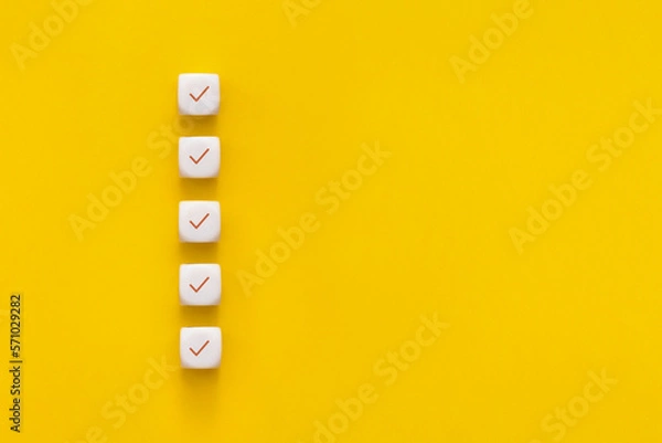 Fototapeta Сubes with check mark on yellow background, Checklist concept with copy space.