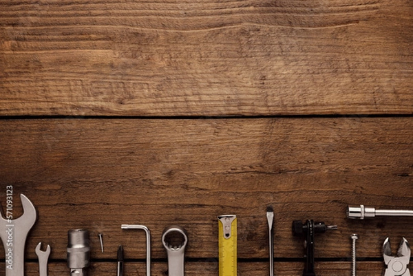 Fototapeta Flat lay with various work tools on wooden background working table. Top view on new hand tool set for repair, construction kit, overhead. Must-have for men. Equipment for building. Industry concept