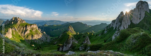 Fototapeta Panorama of green meadow with rocks and rocky mountains in romanian mountains in muntii ciucas with setting sun