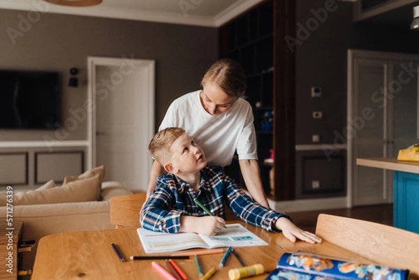 Fototapeta Beautiful mother helping her son with homework in kitchen