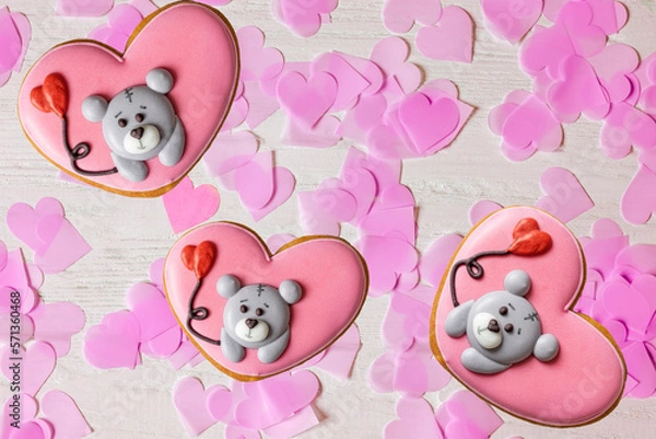 Fototapeta Wooden rough light background with hearts and a Gingerbread in the shape of a heart with a muzzle  teddy bear. Postcard, blank, top view, valentine's day, romantic
