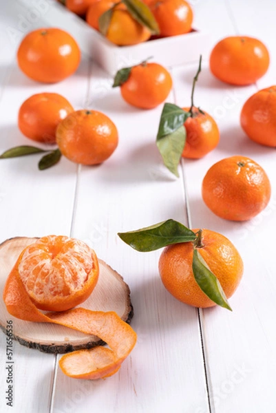 Obraz Fresh clementines with leaves on white wooden table..