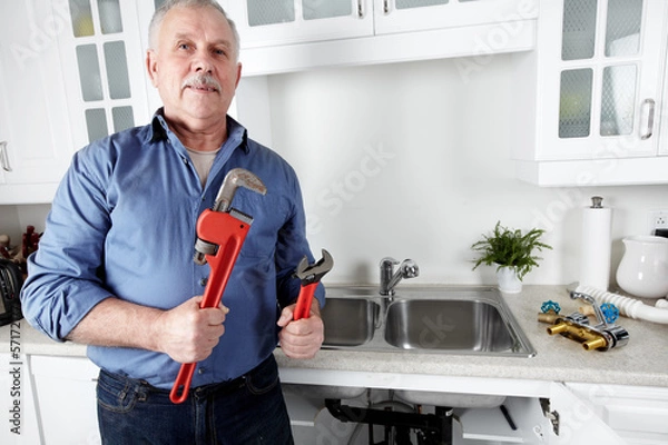 Obraz Plumber in kitchen with a wrench.