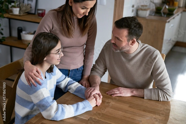 Obraz Caucasian parents talking with teenager girl and sitting around the table